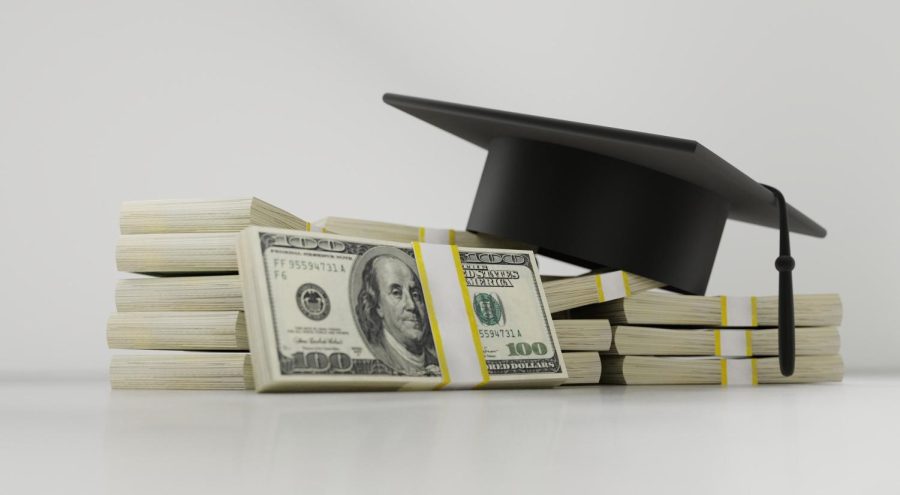A graduation cap atop stacks of one hundred dollar bills | Photo Credit: Pixabay License