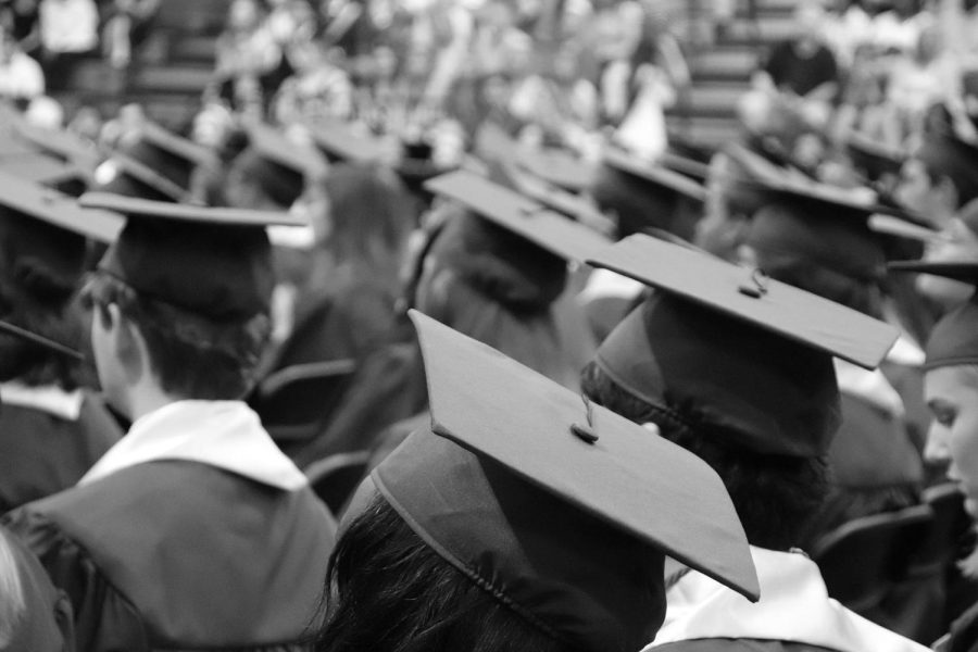 Graduates sitting in their gowns and hats during a graduation ceremony. | Photo Credit: Pixabay License