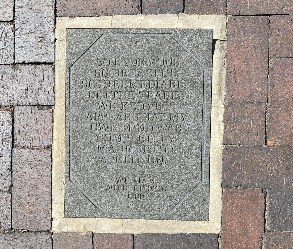 A quote carved into a plaque on brick stones. | Photo Credit: Regina Ivy