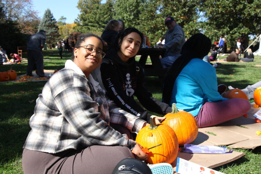 UIS students Melissa Jackson and Xiomara Lopez Carving pumpkins in front of the Carillon at Washington Park. Photo Credit: Regina Ivy