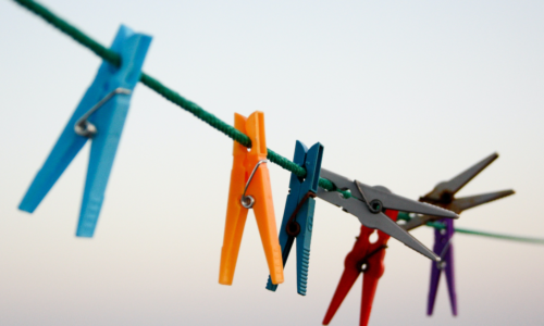A picture containing multiple colored clothes pins on a line | Photo Credit: Unpslash