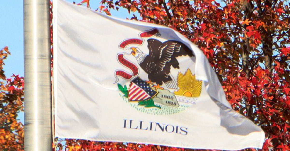 The Illinois state flag flies over the UIS campus in 2021. The current version of the flag, featuring the state seal and name on a white background, was adopted in 1969. Photo by Blake Wood/UIS